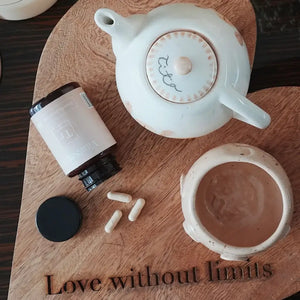 Cápsulas de Tremella VitalSetas junto a una tetera y una taza de cerámica sobre una mesa de madera.